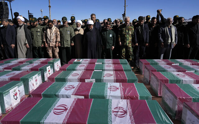 People pray over the flag-draped coffins of victims of a suicide-bomb attack during a funeral ceremony in the city of Kerman, Iran, January 5, 2024. (Vahid Salemi/AP)