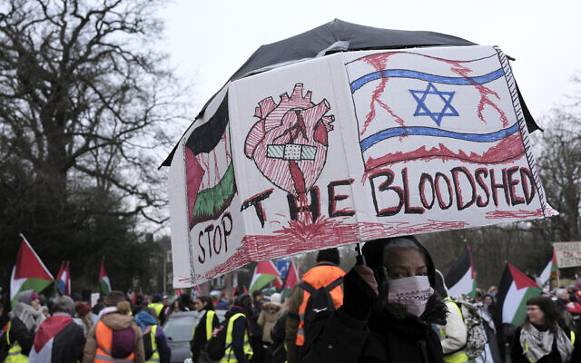 A protester carries a sign, with an Israeli and Palestinian flag and a heart in the middle, during a demonstration outside the International Court of Justice in The Hague, Netherlands, January 11, 2024. The United Nations' top court opened hearings Thursday into South Africa's allegation that Israel's war with Hamas amounts to genocide against Palestinians, a claim that Israel strongly denies. (AP Photo/Patrick Post)