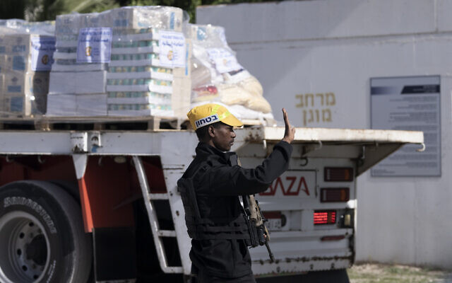 An Israeli security guard signals to trucks carrying humanitarian aid bound for the Gaza Strip arriving to a holding area at Kerem Shalom Crossing on the intersection of two borders: between Egypt and southern Israel and the Gaza Strip and southern Israel, Wednesday, Jan. 10, 2024. (AP Photo/Maya Alleruzzo)