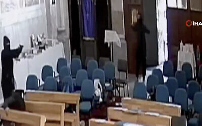 A screenshoot from video footage taken from a CCTV camera, shows two masked men holding guns inside Santa Maria Church in Istanbul, Turkey, January 28, 2024. (IHA via AP)