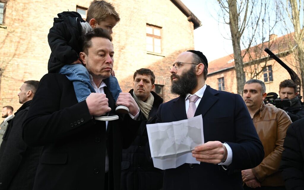 Elon Musk, carrying his son X Æ A-Xii on his shoulders, speaks with Rabbi Menachem Margolin at the Auschwitz-Birkenau museum in Poland on January 22, 2024. (Yoav Dudkevitch)