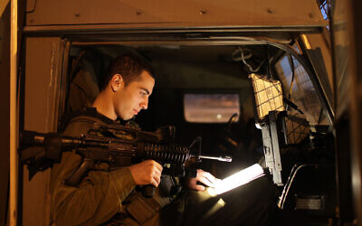 Illustrative: An Israeli soldier reads a book in a military jeep on November 30, 2009. (Nati Shohat/Flash90/File)
