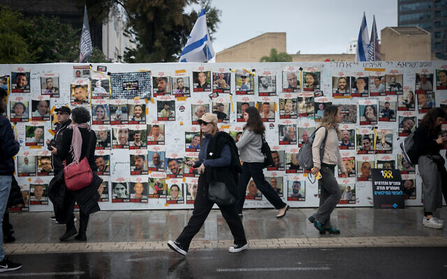 People walk past posters of the hostages still held captive in Gaza at a 24-hour rally marking 100 days since October 7, at 'Hostages Square' in Tel Aviv, on January 14, 2024. (Miriam Alster/Flash90)