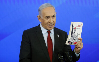 Prime Minister Benjamin Netanyahu holds up an Arabic copy of Adolf Hitler's 'Mein Kampf' found in Gaza during a press conference at the Defense Ministry in Tel Aviv on January 27, 2024 (Tomer Appelbaum/POOL)