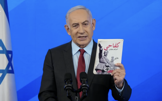 Prime Minister Benjamin Netanyahu brandishes a copy of Adolf Hitler's 'Mein Kampf' in Arabic that was recovered from Gaza as he speaks at a press conference about the ongoing war against Hamas, January 27, 2024. (Screenshot)