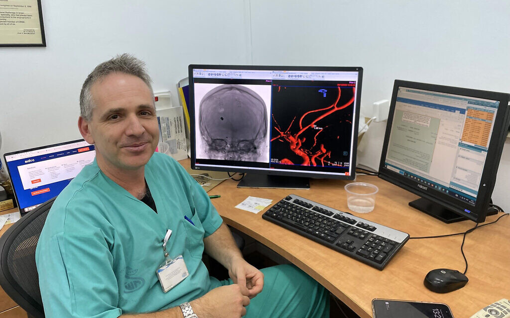 Dr. Gal Yaniv sits next to his computer at Sheba Medical Center that shows how Aidoc platform used AI to identify potentially lethal tiny aneurysm in brain of Nova festival victim and immediately notified relevant medical staff to take action, December 28, 2023. (Renee Ghert-Zand/Times of Israel)