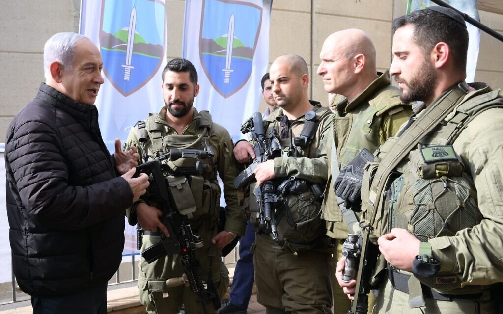 Prime Minister Benjamin Netanyahu, left, speaks to IDF reservists during a visit to the northern border town of Kiryat Shmona on January 8, 2024 (Amos Ben Gershom/GPO)