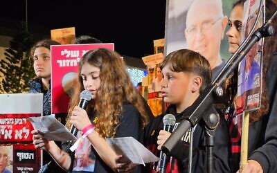 Hili Cooper (left) and Or Nohomovitch (right), tell protesters how they miss their grandfather, Amiram Cooper, held hostage in Gaza, at a rally for the release of Israelis kidnapped by Hamas terrorists, at Hostages Square in Tel Aviv, February 10, 2024. (Hostage and Missing Families Forum)