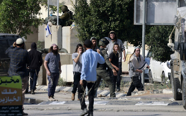 Illustrative: Israeli soldiers scuffle with Jewish settlers from the Einav settlement, trying to storm the West Bank town of Deir Sharaf, near Nablus, November 2, 2023. (Jaafar Ashtiyeh/AFP)