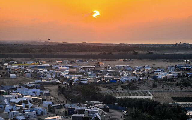 The sun sets over Egypt across the border from the tent camps of displaced Palestinians in Rafah in the southern Gaza Strip on December 31, 2023. (Photo by AFP)