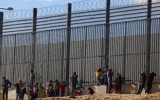 Palestinians stand by the border fence with Egypt in Rafah in the southern Gaza Strip, on January 24, 2024. (AFP)