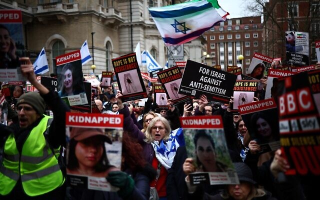 Protesters hold placards and wave Israeli flags as they take part in a demonstration, 'Rape is NOT resistance,'  outside BBC headquarters, in London, on February 4, 2024. (HENRY NICHOLLS/ AFP)