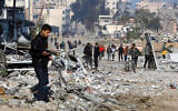 People walk along a street ravaged by Israeli strikes in Gaza City on February 10, 2024. (AFP)