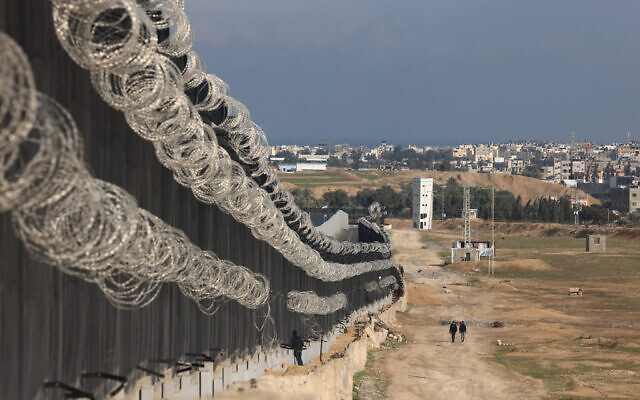 Displaced Palestinians walk next to the border fence between Gaza and Egypt, on February 16, 2024, in Rafah, in the southern Gaza Strip, amid the ongoing war between Israel and the Hamas terror group. (Mohammed Abed/AFP)