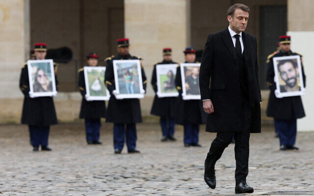 French President Emmanuel Macron walks past French Republican Guards who hold portraits of the French victims of the Oct 7, 2023, Hamas onslaught in Israel, during a ceremony at the Invalides monument, Feb. 7, 2024 (Gonzalo Fuentes/Pool via AP)