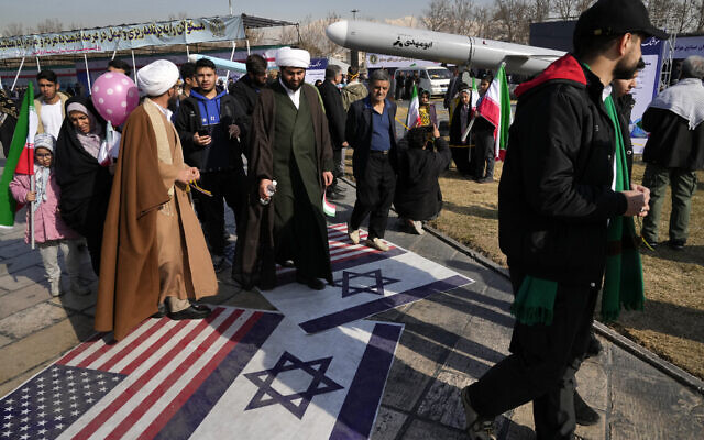 Demonstrators walk on representations of the Israeli and US flags during an annual rally commemorating Iran's 1979 Islamic Revolution in Tehran, Iran, Sunday, Feb. 11, 2024. (AP Photo/Vahid Salemi)