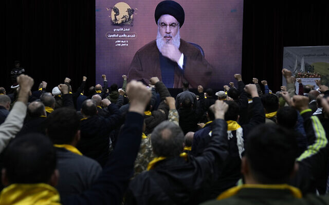 Supporters of the Iranian-backed Hezbollah group raise their fists and cheer, as they listen to a speech by Sayyed Hassan Nasrallah who appears via a video link, during a rally to mark 'wounded resistant's day,' in the southern suburb of Beirut, Lebanon, Tuesday, Feb. 13, 2024. (AP Photo/Hussein Malla)