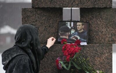 A woman touches a photo of Alexei Navalny after laying flowers paying the last respect to him at the Memorial to Victims of Political Repression in St. Petersburg, Russia on Feb. 17, 2024. (AP Photo/Dmitri Lovetsky)