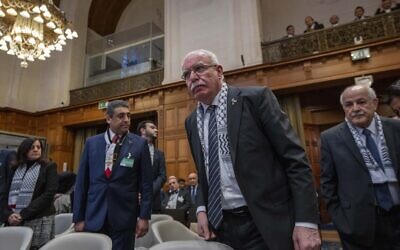 Palestinian Authority foreign minister Riyad Al-Maliki (center) and PA ambassador to the UN Riyad Mansour, right, take their seats at the United Nations' highest court which opened hearings in The Hague, Netherlands, Monday, Feb. 19, 2024.  (AP Photo/Peter Dejong)