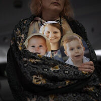 A woman holds a mask depicting the faces of Shiri Bibas and her sons Kfir and Ariel, Israelis who are being held hostage in the Gaza Strip by the Hamas terror group, during a protest demanding the release of the hostages from Hamas captivity, in Tel Aviv, Israel, Wednesday, February 21, 2024. (AP Photo/Oded Balilty)