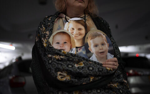 A woman holds a mask depicting the faces of Shiri Bibas and her sons Kfir and Ariel, Israelis who are being held hostage in the Gaza Strip by the Hamas terror group, during a protest demanding the release of the hostages from Hamas captivity, in Tel Aviv, Israel, Wednesday, February 21, 2024. (AP Photo/Oded Balilty)