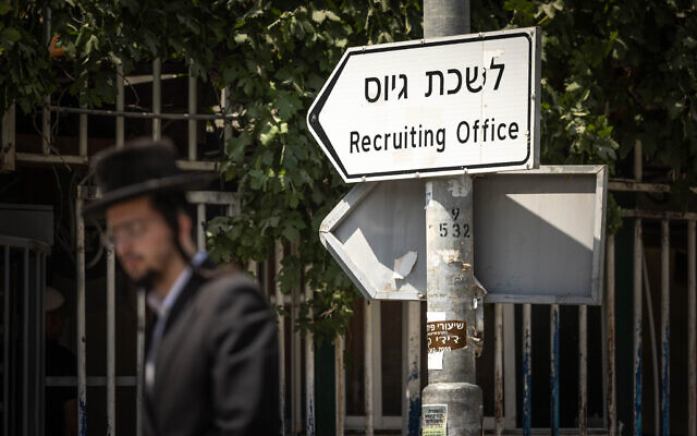 Ultra-Orthodox Jews walk outside an army recruitment office in Jerusalem, August 16, 2023. (Chaim Goldberg/Flash90)