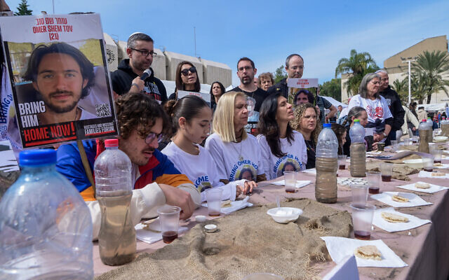 Families of Israelis held hostage by Hamas terrorists in Gaza gather around a table at 'Hostage Square' in Tel Aviv, February 24, 2024. (Avshalom Sassoni/Flash90)