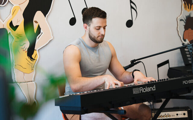 The young plays keyboard in the music studio at the young vets' department at Beit Halochem in Tel Aviv, 2024. (Mark Nomdar)