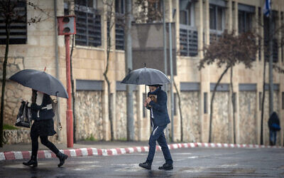 People take cover from the rain in Jerusalem, January 28, 2024. (Chaim Goldberg/Flash90)