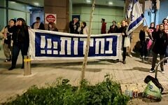 In a photo provided by anti-government activists, protesters hold a banner calling for elections outside the home of Intelligence Minister Gila Gamliel, in Tel Aviv, February 22, 2024. (Udi Salmanovich)