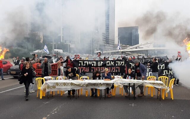 In a photo provided by activists, hostages' families set up a Shabbat dinner table and urge an immediate deal to release their loved ones from captivity, blocking the Ayalon Highway in Tel Aviv, February 23, 2024. (Adar Eyal)