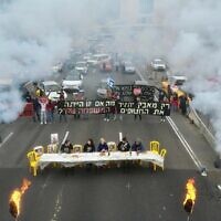In a photo provided by activists, hostages' families set up a Shabbat dinner table and urge an immediate deal to release their loved ones from captivity, blocking the Ayalon Highway in Tel Aviv, February 23, 2024. (Amir Terkel)