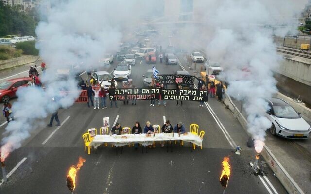 In a photo provided by activists, hostages' families set up a Shabbat dinner table and urge an immediate deal to release their loved ones from captivity, blocking the Ayalon Highway in Tel Aviv, February 23, 2024. (Amir Terkel)