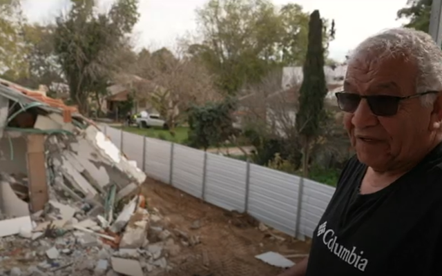 Yehuda Arussi stands in front of what used to be his home in Kibbutz Be'eri on February 12, 2024. (Screen capture/Channel 12)