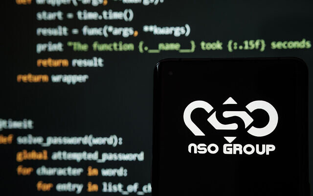 Illustrative: NSO Group logo seen on a smartphone in front of a laptop showing hacking code (mundissima/Shutterstock.com)