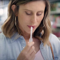 A woman (played by actor and influencer Alina Levy) uses Salistick saliva pregnancy test while shopping at a drugstore in Israel in YouTube ad for the new product, March 2024. (Screenshot/YouTube)