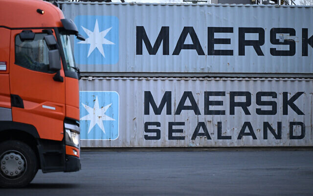 A truck driver with his vehicle makes his way past containers with the logo of Danish shipping giant Maersk and Maersk Sealand stacked at a transshipment station in Frankfurt am Main, western Germany, on January 23, 2024 (Kirill KUDRYAVTSEV / AFP)