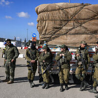 Israeli soldiers stand by an Egyptian truck bringing in humanitarian aid supplies into the Gaza Strip at the Kerem Shalom border crossing, February 6, 2024. (Menahem Kahana/ AFP)