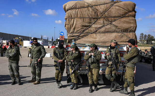Israeli soldiers stand by an Egyptian truck bringing in humanitarian aid supplies into the Gaza Strip at the Kerem Shalom border crossing, February 6, 2024. (Menahem Kahana/ AFP)