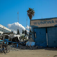 People walk past the damaged Gaza City headquarters of the United Nations Relief and Works Agency for Palestine Refugees (UNRWA) on February 15, 2024. (AFP)