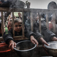 Displaced Palestinian children gather to receive food at a government school in Rafah in the southern Gaza Strip on February 19, 2024. (Mohammed Abed/AFP)