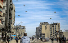 Palestinians run along a street as humanitarian aid is airdropped in Gaza City on March 1, 2024 (Photo by AFP)