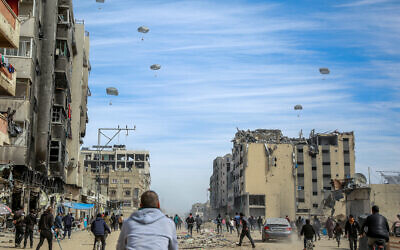 Palestinians run along a street as humanitarian aid is airdropped in Gaza City on March 1, 2024 (Photo by AFP)