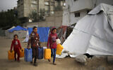 Palestinian girls carry water containers along a street in Rafah in the southern Gaza Strip on March 3, 2024. (AFP)