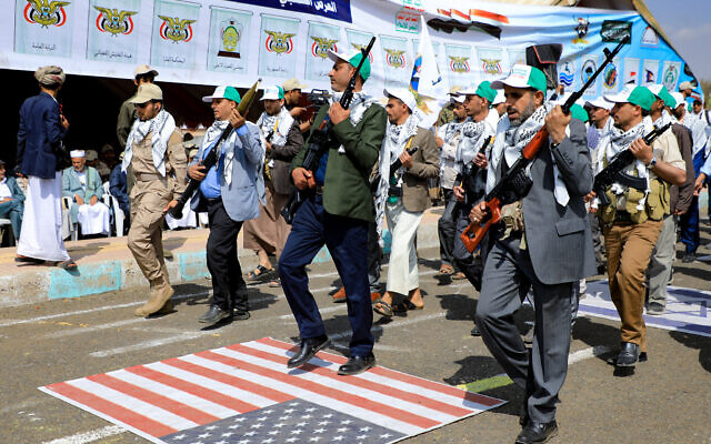 Armed Yemeni civil servants step on a US flag as they take part in a parade following 12 days of military training in the Houthi-run capital Sanaa on March 9, 2024, (MOHAMMED HUWAIS / AFP)