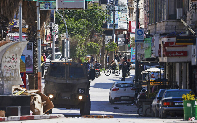 An Israeli military vehicle patrols along a street during a raid at the Jenin refugee camp area in the West Bank on March 12, 2024. (Photo by Jaafar ASHTIYEH / AFP)