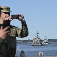 US Army soldiers take photographs of the USAV Monterrey (not pictured) as it pulls away from the pier to join the USAV SP4 James A. Loux (R), the USAV Wilson Wharf (C) and the USAV Matamoros (L) as they sail off the Joint Base Langley-Eustis during a media preview of the 7th Transportation Brigade deployment in Hampton, Virginia, on March 12, 2024.(Roberto Schmidt/AFP)