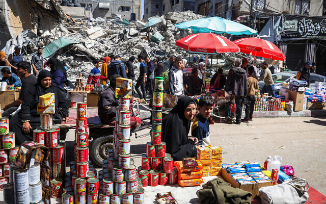 Palestinians walk at a makeshift market next to building rubble during the Muslim holy fasting month of Ramadan in Rafah in the southern Gaza Strip on March 12, 2024 group Hamas. (AFP)
