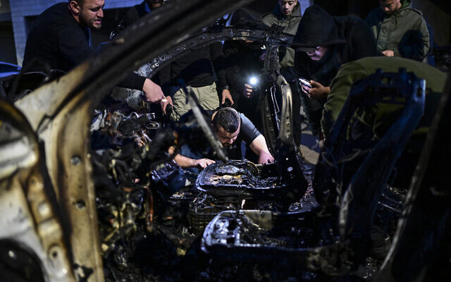 Palestinians inspect a car that was hit by an Israeli airstrike, in the West Bank city of Jenin, March 20, 2024.. (Ronaldo Schemidt/AFP)