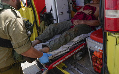 Israeli security forces in Kiryat Shoma evacuate a wounded Thai man after he was hit by an anti-tank missile fired from Lebanon, March 4, 2024. (AP Photo/Ariel Schalit)
